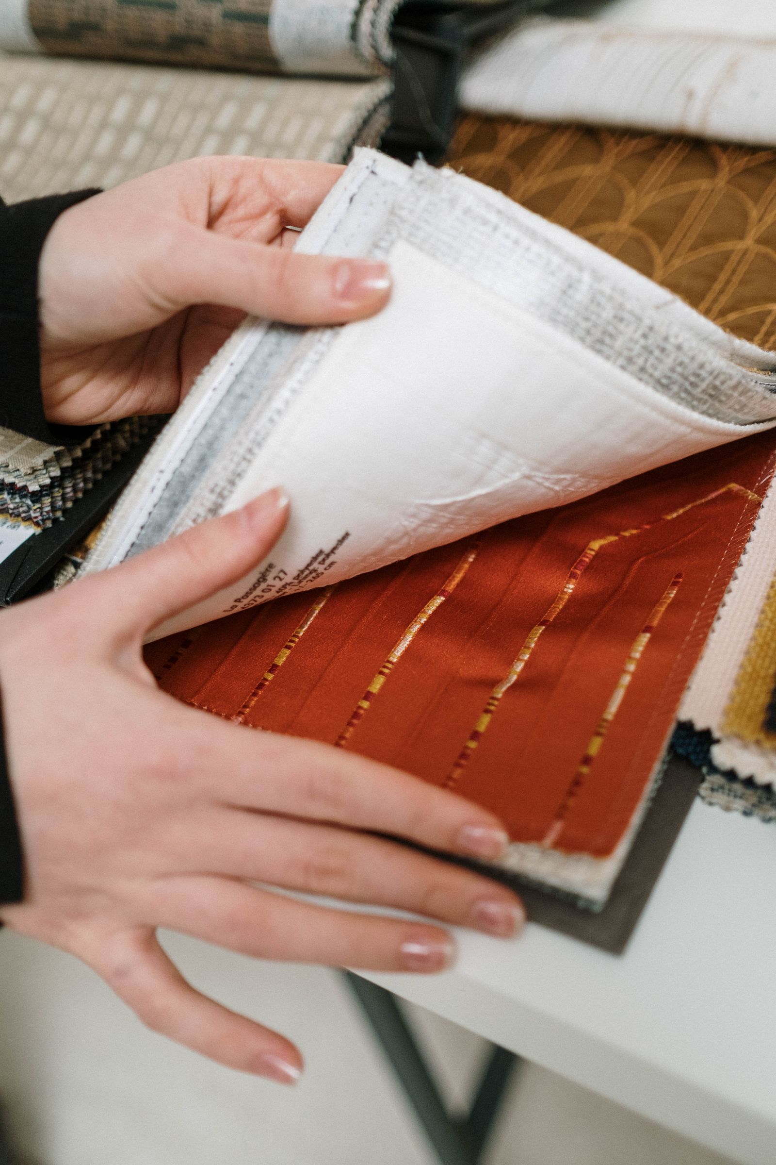 A designer flipping through a book of fabric swatches
