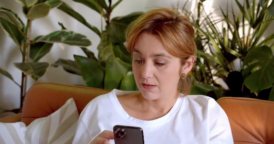 A woman shopping on her phone from her couch